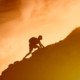 Silhouette of man climbing up a mountain