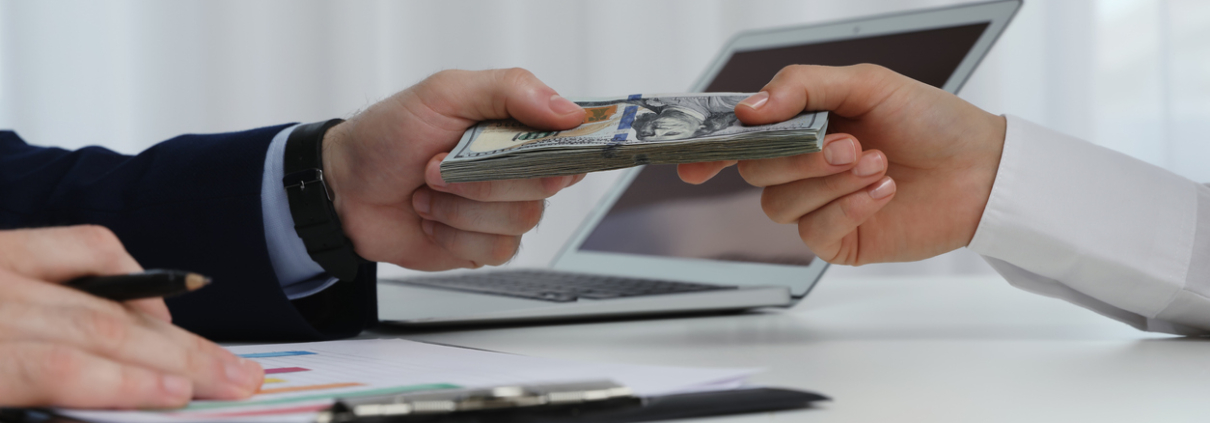 Cashier giving money to businesswoman at desk in bank, closeup